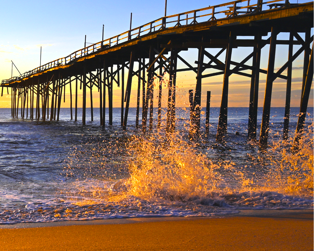 Pier with waves crashing against it at sunset